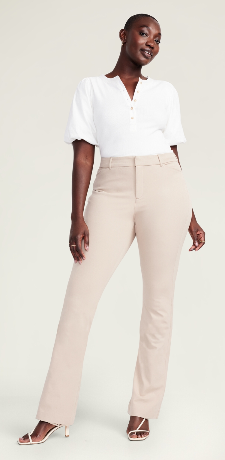 A female model wearing high waist light colored flare style pants.