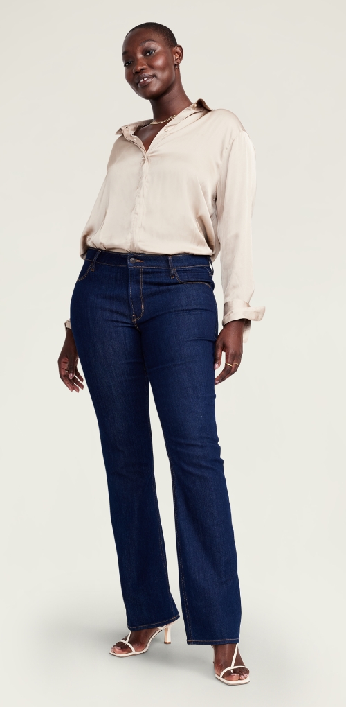 Boot-cut navy blue jeans paired with a neutral silk blouse.