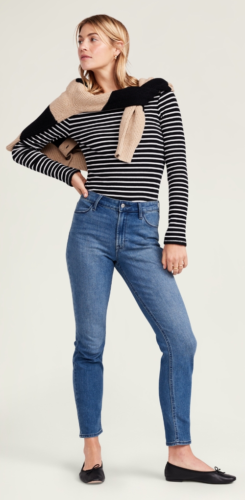 A female model in medium rise dark blue slimming jeans.