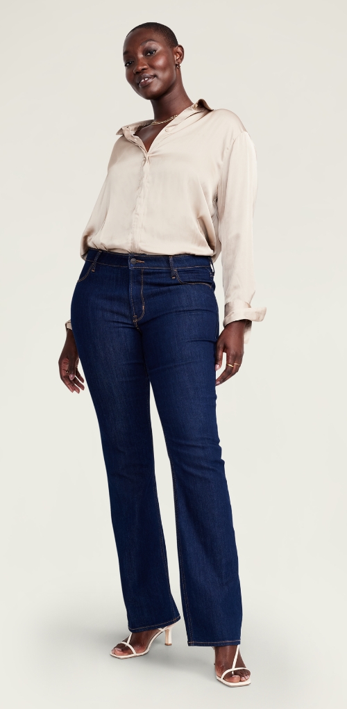 Boot-cut navy blue jeans paired with a neutral silk blouse.