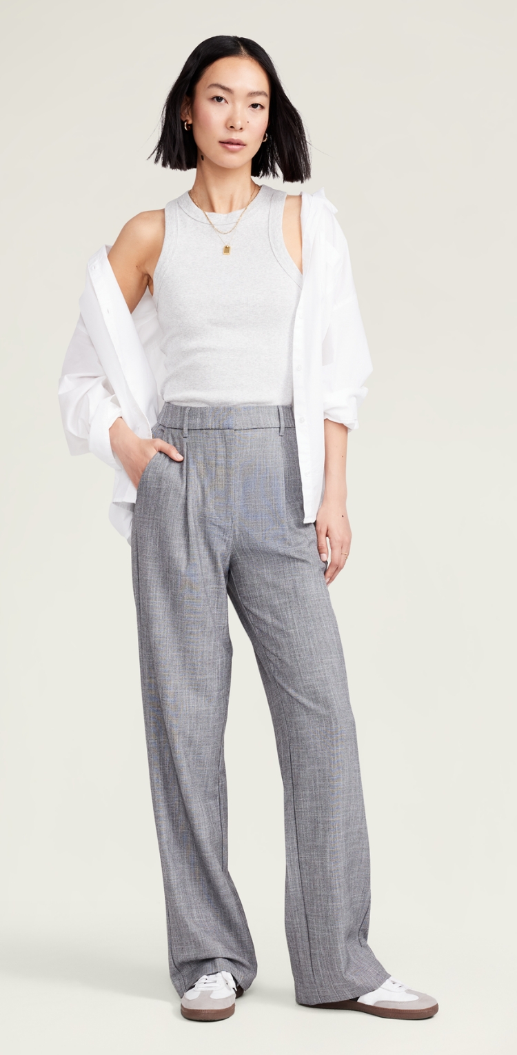 A female model in grey wide leg pleated trousers.