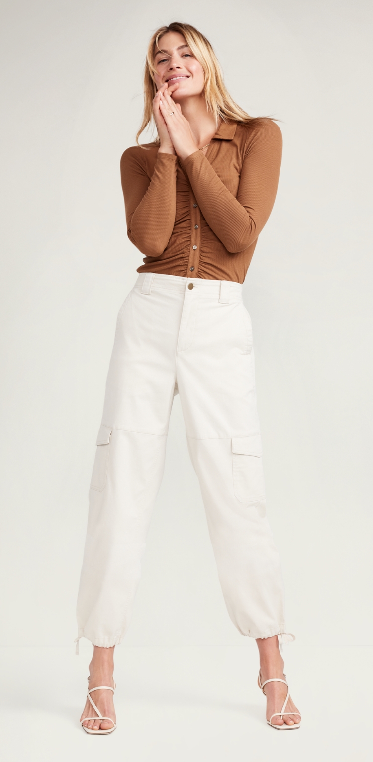 A female model in white and beige cargo pants with pockets on the legs. 