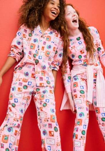 Two young girls wearing gender-neutral printed pajama sets.