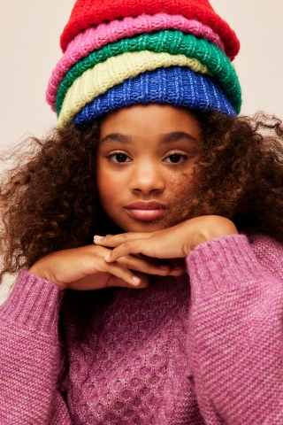 A young female model wearing a pink sweater and winter accessories