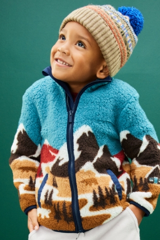 A toddler boy wearing a printed zip-up long sleeve cozy fleece & beanie