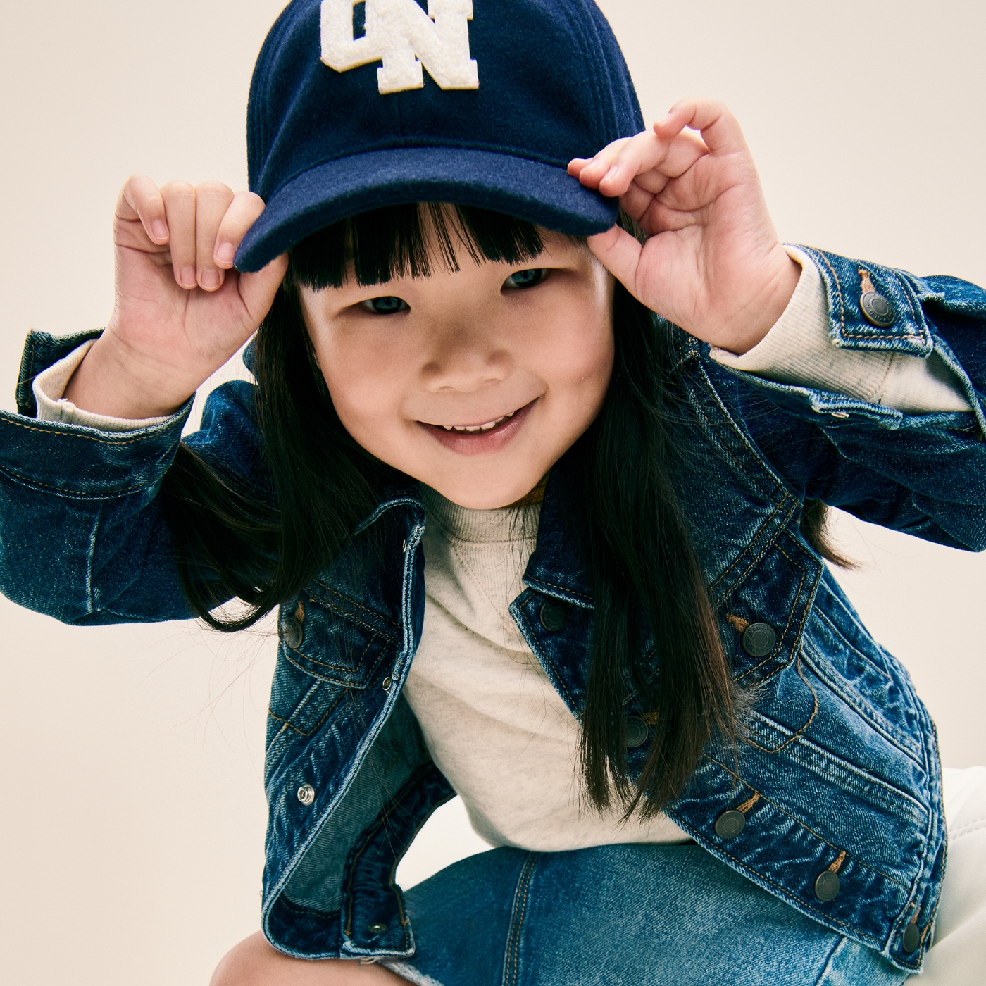 A toddler girl dressed in a jean jacket, sweater, and matching skirt
