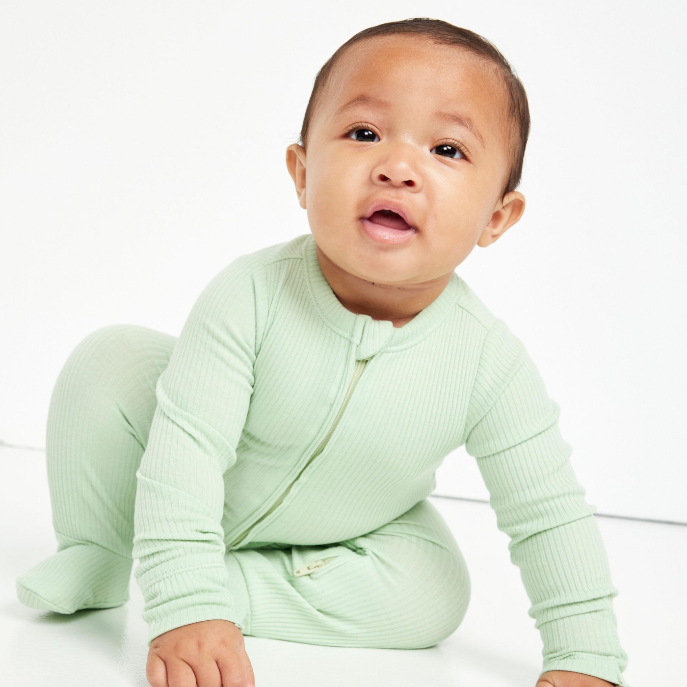 A baby girl dressed in unisex mint color onesie.