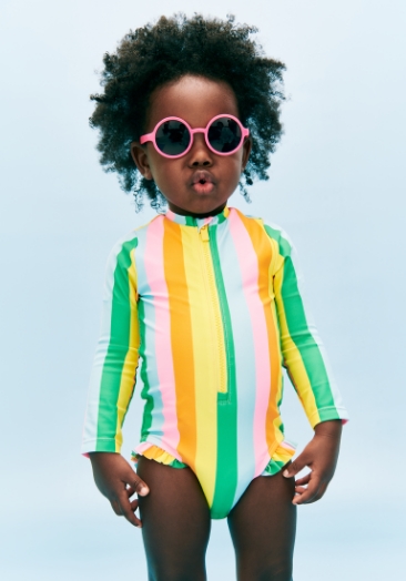 A young girl model wearing multi stripe Printed Ruffle-Trim Rashguard One-Piece Swimsuit for Baby.