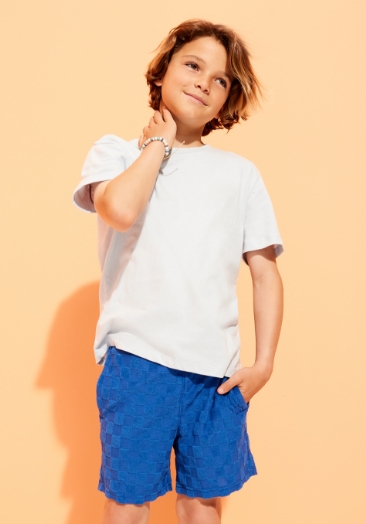 Young boy model wearing white t-shirt and blue shorts.