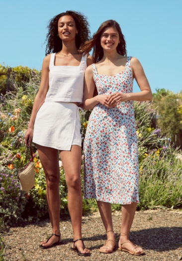 Two female models wearing white skirt and top set and floral print midi dress.