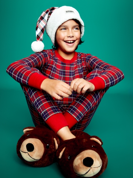 A boy in a matching pajama set and bear slippers.