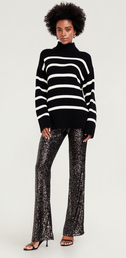 A woman dressed in black sequin shine pants paired with a sweater and strappy heels.